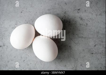 Blick von oben auf drei weiße Eier auf dem grauen Tisch Stockfoto
