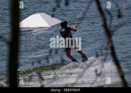 Langenfeld, Deutschland. Juni 2025. Ein Wasserskifahrer genießt das Sommerwetter in einer Wasserski-Anlage in Langenfeld. Der Deutsche Wetterdienst erwartet viel Sonne und Hitze für den Beginn der Woche. Quelle: Henning Kaiser/dpa/Alamy Live News Stockfoto