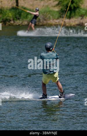 Langenfeld, Deutschland. Juni 2025. Wasserskifahrer genießen das Sommerwetter in einer Wasserski-Anlage in Langenfeld. Der Deutsche Wetterdienst erwartet viel Sonne und Hitze für den Beginn der Woche. Quelle: Henning Kaiser/dpa/Alamy Live News Stockfoto