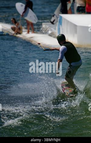 Langenfeld, Deutschland. Juni 2025. Ein Wasserskifahrer genießt das Sommerwetter in einer Wasserski-Anlage in Langenfeld. Der Deutsche Wetterdienst erwartet viel Sonne und Hitze für den Beginn der Woche. Quelle: Henning Kaiser/dpa/Alamy Live News Stockfoto