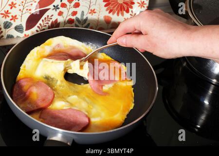 Rührei in der Pfanne mit Würstchen in einer schwarzen Pfanne Stockfoto