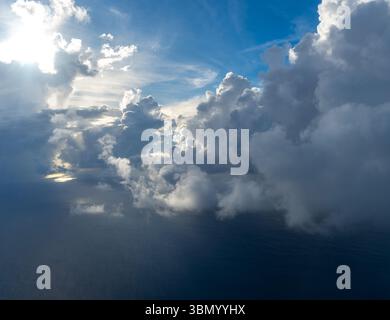 Majestätische Wolken, die von der Sonne beleuchtet werden, schaffen einen dramatischen Himmel, der von oben betrachtet wird. Das helle Sonnenlicht steht im Kontrast zum tiefblauen Himmel und dem schattigen Clou Stockfoto