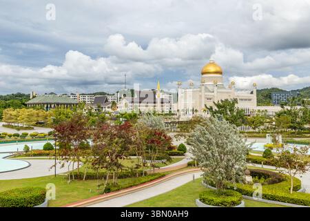 Zentraler Stadtgarten der Omar Ali Saifuddien Moschee goldene Kuppeln und Minarette mit Innenstadt im Hintergrund, Bandar Seri Begawan, Borneo, Sultanat Stockfoto