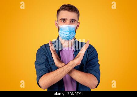 Kampf gegen Coronavirus Konzept. Ernst kaukasischen Mann im Gesicht Maske gestikulierenden STOPP auf grauen Studio-Hintergrund Stockfoto