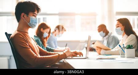 Internationale Menschen tragen medizinische Masken mit Laptop Stockfoto