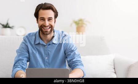 Mann am Laptop-Computer arbeitet online und lächelt zu Hause Stockfoto