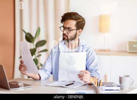 Junger Arabischer Geschäftsmann, Der Mit Papieren Am Schreibtisch Im Büro Arbeitet Stockfoto