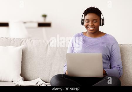 Schwarze Frau, die am Computer arbeitet und ein Headset trägt Stockfoto
