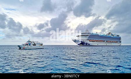 Ein Blick auf ein Kreuzfahrtschiff Emerald Princess vor Anker in der Nähe von Princess Cays auf den Bahamas und ein kleines Shuttleboot, das Passagiere zur Entspannung an Land bringt Stockfoto