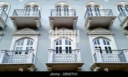 Fragment der Fassade des Gebäudes mit durchbrochenen Balkonen mit kunstvollen Eisengeländern und klassisch weißen Zierleisten Stockfoto