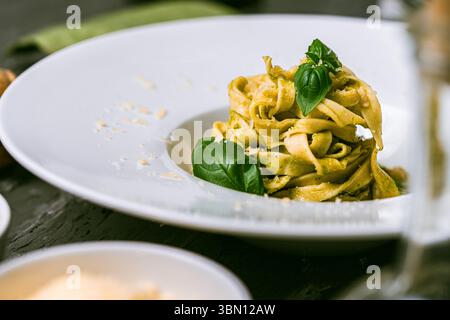 Fituccine Nudeln mit Basilikum- und Pinienkernpesto auf einem weißen Teller mit Gabel. Fituccine al Pesto Pasta nach traditionellem italienischem Rezept. Hoch q Stockfoto