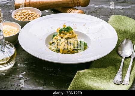 Fituccine Nudeln mit Basilikum- und Pinienkernpesto auf einem weißen Teller mit Gabel. Fituccine al Pesto Pasta nach traditionellem italienischem Rezept. Hoch q Stockfoto