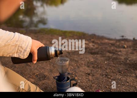 Kaffeefilterung. Hispanischer Mann, der heißes Wasser gießt, Kaffee für das Frühstück im Freien am frühen Morgen an einem Bach im El Palmar National kocht Stockfoto