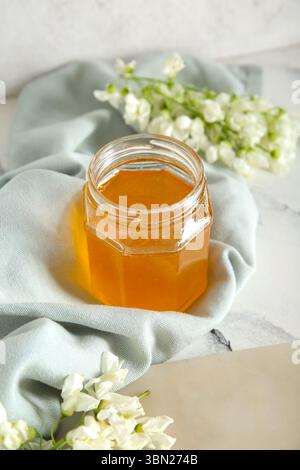 Glas Honig mit Akazienblüten auf hellem Hintergrund, Nahaufnahme Stockfoto