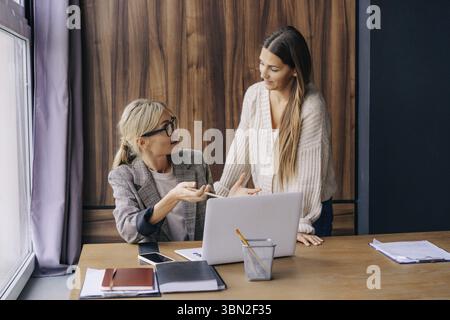 Zwei weibliche Kollegen in einem Arbeitsbüro diskutieren über ein Projekt Stockfoto