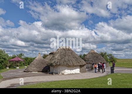 Touristen besuchen die Nachbauten neolithischer Häuser im Besucherzentrum Stonehenge. Amesbury, Wiltshire, Südengland, Großbritannien Stockfoto
