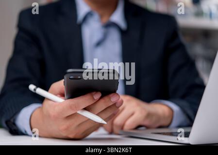 Geschäftsmann, der Smartphone mit Stift hält, aus der Ferne arbeitet. Ideal für mobiles Büro, digitale Kommunikation, Technologienutzung und professionelle Unternehmen Stockfoto