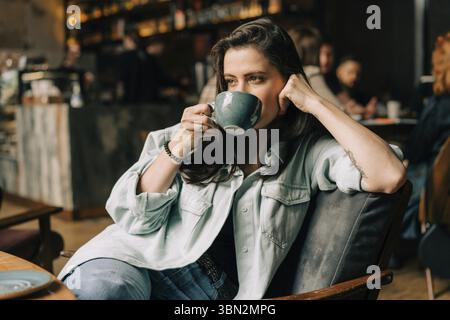 Junge schöne Frau, die in einem Café sitzt, trinkt Kaffee Stockfoto