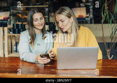 Zwei Geschäftsfrauen diskutieren ein Projekt, während sie in einem Café sitzen Stockfoto