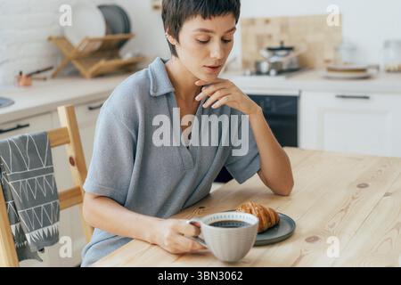 Frau, die in der Küche sitzt und frühstückt Stockfoto