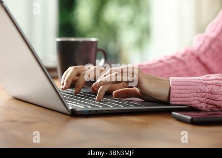 Nahaufnahme Porträt einer Frau, die zu Hause auf einem Holztisch auf einem Laptop schreibt Stockfoto