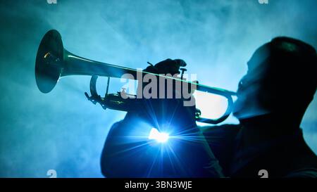 Silhouette eines Trompetenspielers vor blauem rauchigen Hintergrund Stockfoto