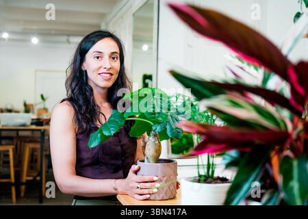 Floristin steht im Blumenladen, tausendjährige Kleinunternehmer-Eigentümerin mit ihren Pflanzen und Blumen Stockfoto