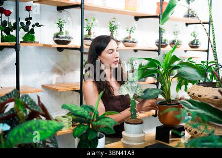 Floristin steht im Blumenladen, tausendjährige Kleinunternehmer-Eigentümerin mit ihren Pflanzen und Blumen Stockfoto