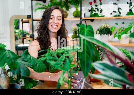Floristin steht im Blumenladen, tausendjährige Kleinunternehmer-Eigentümerin mit ihren Pflanzen und Blumen Stockfoto