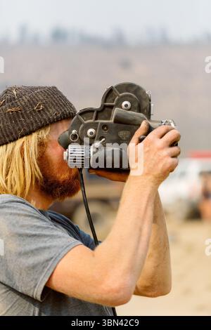 Kameramann filmt mit Super 8-Filmkamera in Wüstenlandschaft Stockfoto