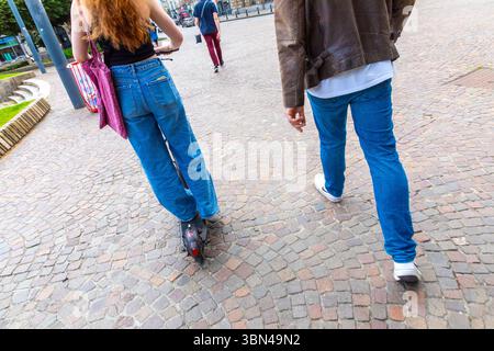 Ein Paar auf der Straße. Er zu Fuß, sie auf dem Roller. Stockfoto
