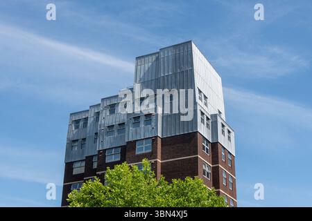 Ein mehrstöckiges städtisches Wohngebäude mit Metallverkleidung auf einem Backsteinsockel Stockfoto