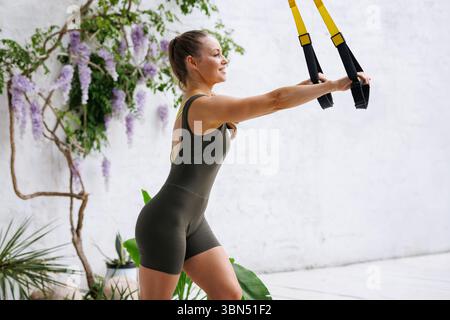 Frau, die mit Hängebändern im Freien fördert Kraft gesunde Lebensweise und Körpergewicht funktionelles Training Stockfoto