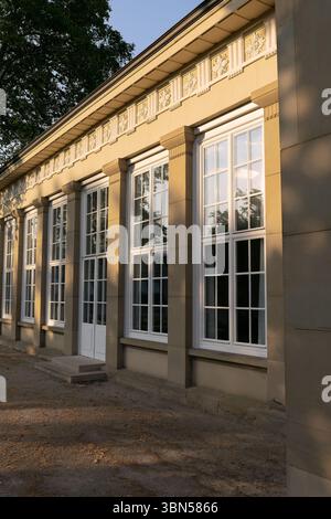 Vier große alte Fenster in einem alten Gebäude. Ein einstöckiges Gebäude mit großen Fenstern und einem Eingang in der Mitte. Wunderschöne, hohe weiße Fenster Stockfoto