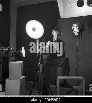 Pressphotograf der 1940er Jahre Anders Swahn stellte eine Kamera in der Hand und posierte für ein Foto in einem Fotostudio mit Lichtern. Eine Rolleiflex-Kamera ist auf dem Stativ vor ihm montiert. Eine Standardausrüstung für Pressefotografen zu dieser Zeit. 1948. Anders Svahn Stockfoto