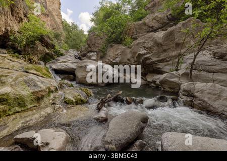 Devil's Bridge, ein natürlicher Travertinbogen, der den tiefen Vorotan River überspannt. Unten bilden warme Mineralquellen farbenfrohe Stalaktiten in versteckten Grotten. Stockfoto