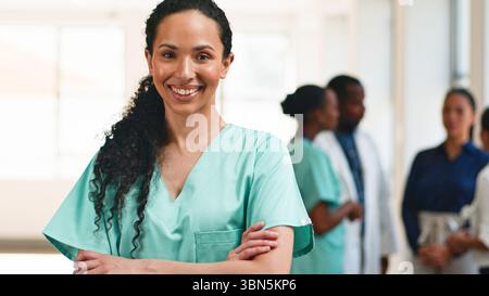 Selbstbewusste Pflegekraft im Scrubs im Team mit medizinischen Fachkräften Stockfoto