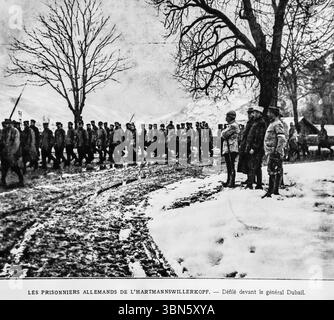 Deutsche Kriegsgefangene aus der Schlacht von Hartmannswillerkopf ziehen auf diesem Foto aus dem Ersten Weltkrieg 1916 an General Auguste Dubail vorbei. An der verschneiten Vogesenfront im Elsass festgehalten, spiegelt die Szene den bitteren Gebirgskrieg zwischen französischen und deutschen Truppen wider. Ursprünglich in L’Illustration veröffentlicht, dokumentiert dieses Bild einen seltenen Moment formeller militärischer Überprüfung inmitten von Grabenkonflikten. Stockfoto