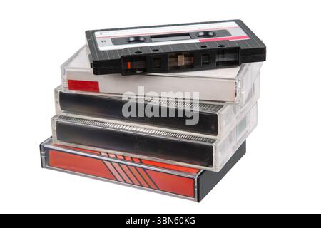 Retro-Magnetbandkassette auf einem Stapel von Kunststoffhüllen, isoliert auf weißem Hintergrund, symbolisiert analoge Tonaufnahmen Stockfoto