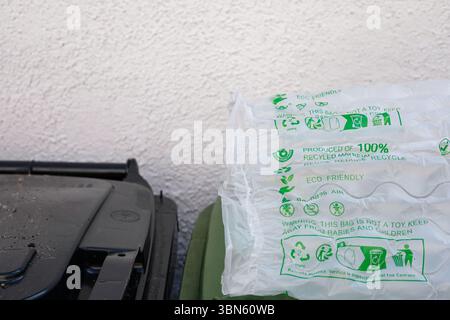 Kunststoff-Luftkissen aus recyceltem Material mit grünen umweltfreundlichen Symbolen und Text. Abfallbehälter oder Abfallbehälter daneben. Stockfoto