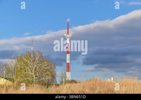 Der Kommunikationsturm ist rot und weiß lackiert. Ein Kommunikationsturm in ländlichen Gebieten. Stockfoto