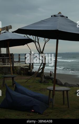 Bali, Indonesien - 27. Mai 2025: Sitzsack Stühle, Tische und Sonnenschirme am Strand in der Nähe des Meeres Stockfoto