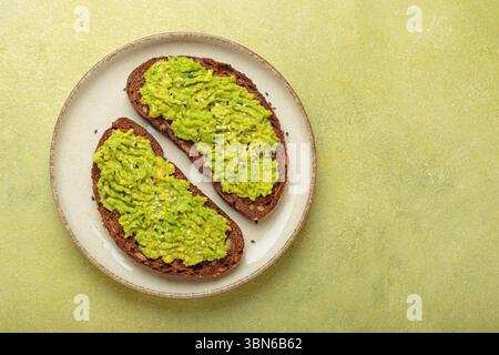 Zwei Scheiben Avocado Toast mit Sesamsamen auf Roggenbrot, Blick von oben auf hellgrünem Hintergrund Stockfoto