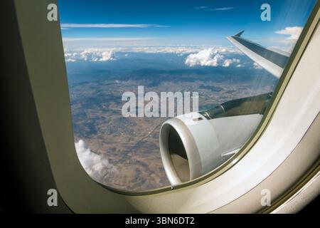 Landschaft, Wolken, Motor und Flügel durch das Flugzeugfenster gesehen Stockfoto
