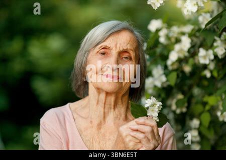 Nahaufnahme einer älteren Frau, die Jasmine mit verschwommenem Hintergrund hält Stockfoto
