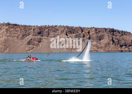 Cove Palisades State Park, Oregon, USA - 1. September 2018: Ein Mann fliegt auf dem See, während zwei andere mit einem Jet Ski fahren. Stockfoto