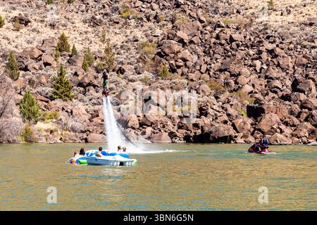 Cove Palisades State Park, Oregon, USA - 1. September 2018: Ein Mann fliegt auf dem Flyboard, während andere von einem Boot und einem Jet-Ski aus zusehen und Wassersport genießen. Stockfoto