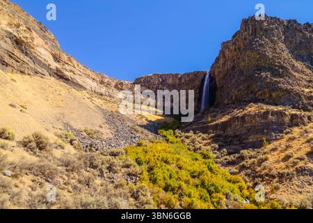 Cove Palisades State Park, Oregon, USA - 2. September 2018: Ein Wasserfall stürzt über eine Klippe, umgeben von felsigem Gelände und karger Vegetation. Stockfoto