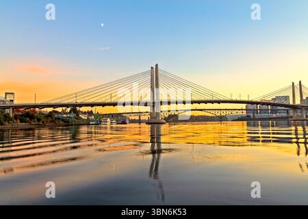 East Bank Esplanade, Portland, Oregon – 18. November 2018: Die Sonne geht hinter den Brücken über den Willamette River unter und strahlt ein goldenes Leuchten aus. Stockfoto