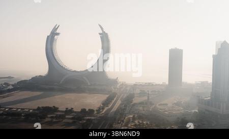 Doha, Katar [24. Februar 2025]: Ein nebeliger Morgen in Doha mit Wolkenkratzern, die teilweise im Nebel verborgen sind und eine geheimnisvolle und ruhige Stadtlandschaft schaffen. Stockfoto